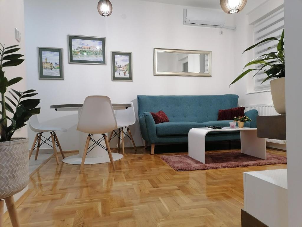 uma sala de estar com um sofá azul e uma mesa em Carmen deluxe em Novi Sad