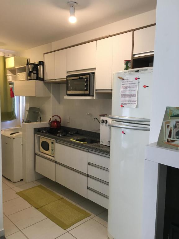 La cuisine est équipée de placards blancs et d'un réfrigérateur blanc. dans l'établissement Apartamento Rocha Cuiabá, à Cuiabá