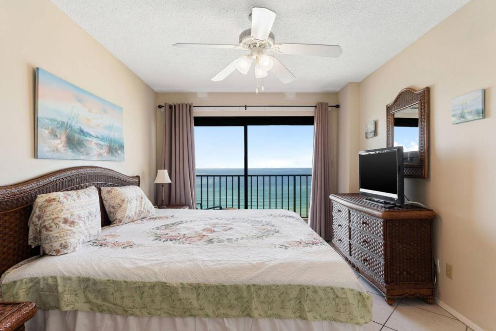a bedroom with a bed with a television and a balcony at Commodore 1002 in Panama City Beach