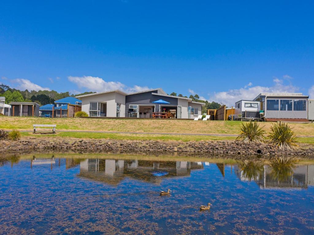 a row of houses next to a body of water at Lake on Scott - Cooks Beach Holiday Home in Cooks Beach