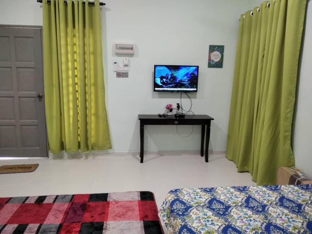 a living room with green curtains and a television at Sacha Homestay in Baling