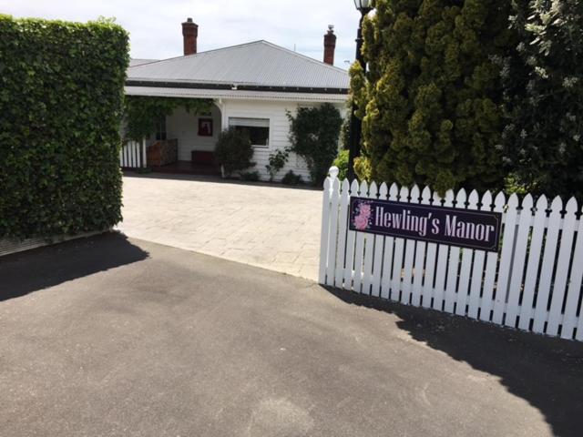 una cerca blanca con un cartel delante de una casa en Hewling's Manor en Geraldine