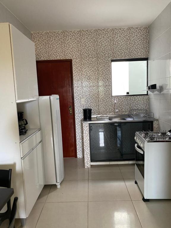 a kitchen with a white refrigerator and a sink at Mellim Residence in Maragogi