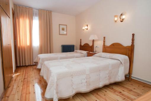 Habitación de hotel con 3 camas con sábanas blancas en Hotel Llacs De Cardos, en Tavascán