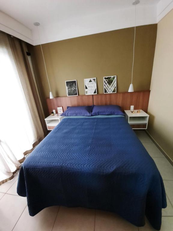 1 cama azul en un dormitorio con 2 mesas en Flat Quartier Aldeia das Águas, en Barra do Piraí