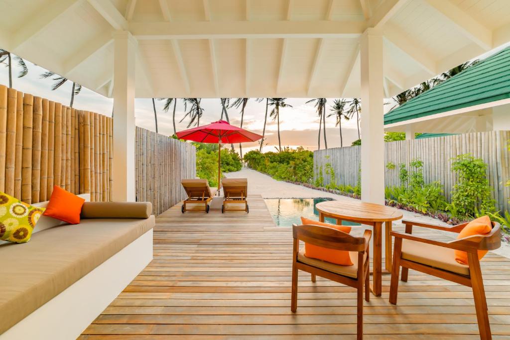 a patio with a table and chairs and an umbrella at Siyam World Maldives - 24-Hour Premium All-inclusive with Free Transfer in Dhigurah