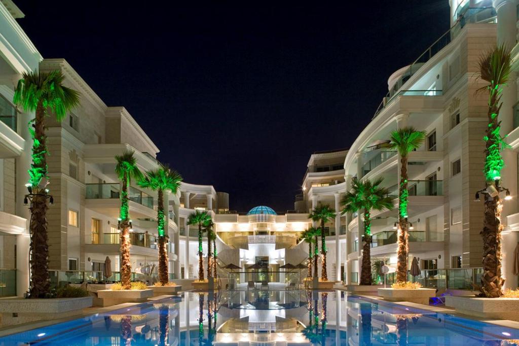 a hotel courtyard with palm trees in front of a building at YalaRent Palmore Resort apartments in Eilat