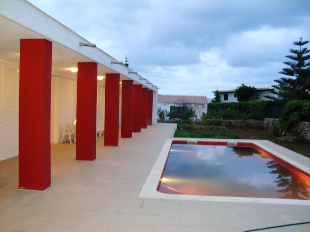 a swimming pool in a building with red columns at 3 bedrooms villa at Cap d'en Font 800 m away from the beach with sea view private pool and enclosed garden in Cap d'en Font
