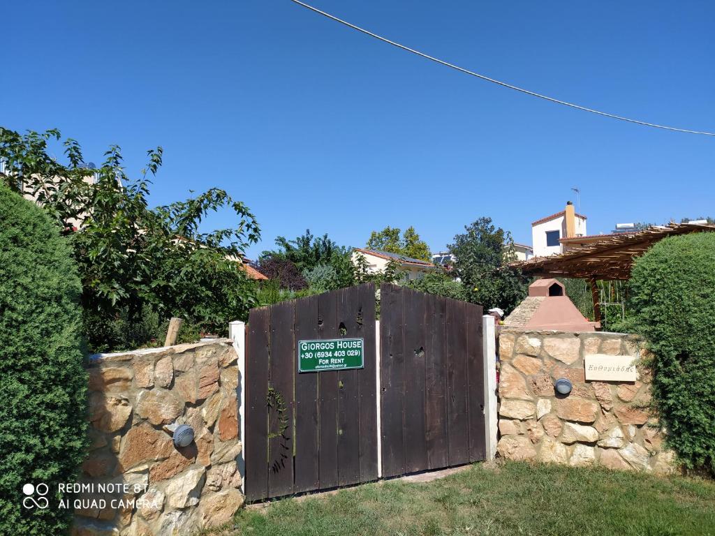 ein Tor in einer Steinmauer mit einem Schild darauf in der Unterkunft Giorgos Garden House in Keramotí