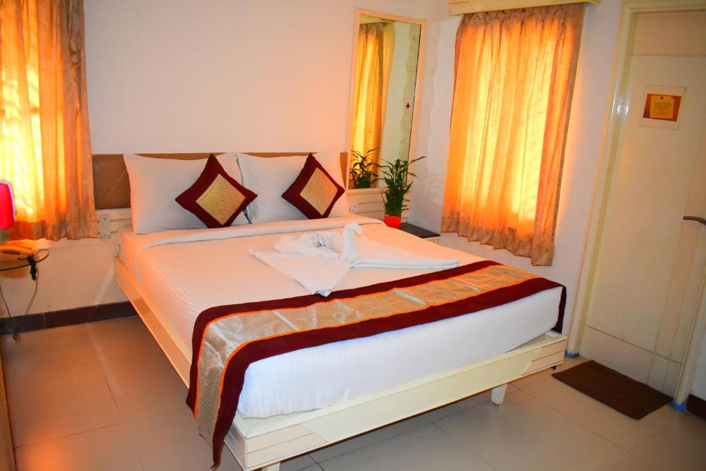 a bedroom with a large bed with orange curtains at Aishwarya Residency in Tiruvannāmalai