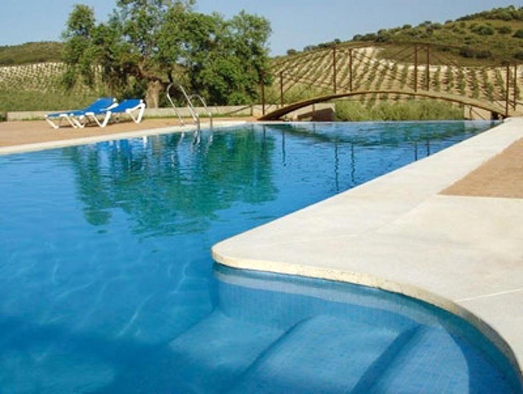 a blue swimming pool with a bridge in the background at Charming House in Estepa with Shared Pool in Lora de Estepa