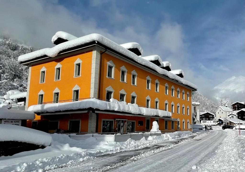 ein orangefarbenes Gebäude mit Schnee drauf in der Unterkunft Boutique und Bier Hotel des alpes in Fiesch