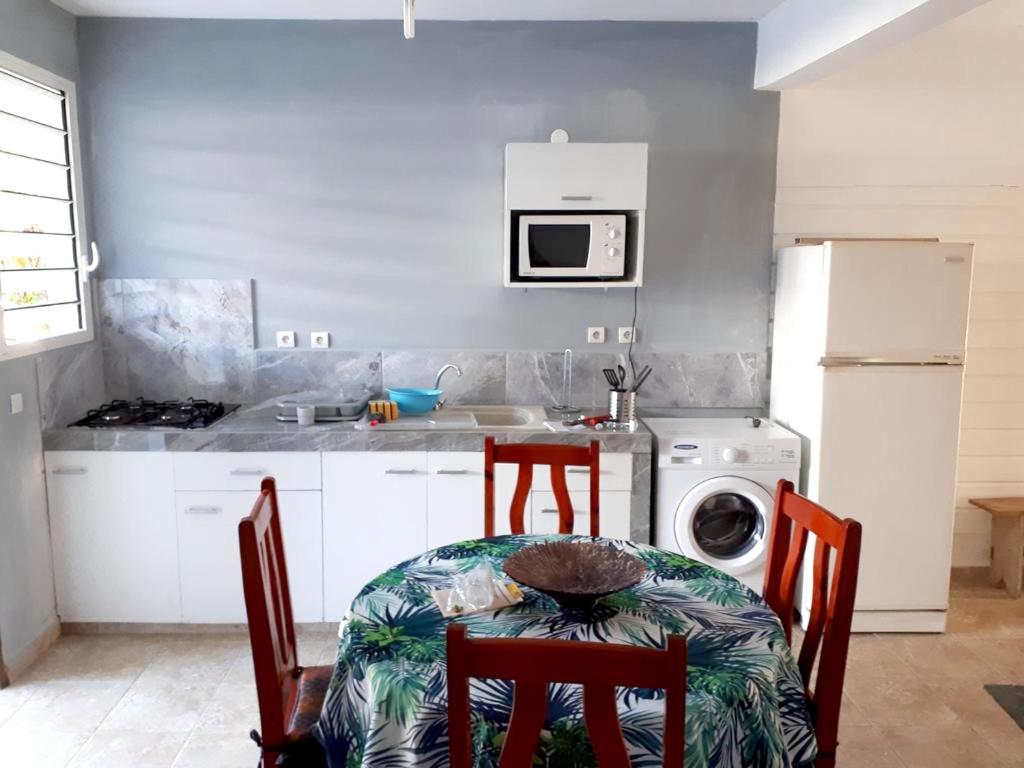 a kitchen with a table and chairs and a washing machine at Maison de 2 chambres avec jardin clos a Morne A l'Eau a 2 km de la plage in Morne-à-lʼEau