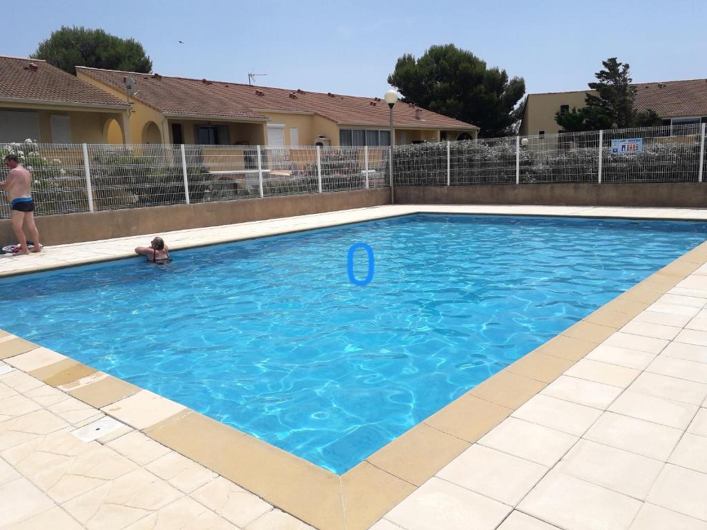 - une piscine avec un enfant dans l'eau dans l'établissement Maison charmante à Gruissan avec piscine partagée, à Gruissan