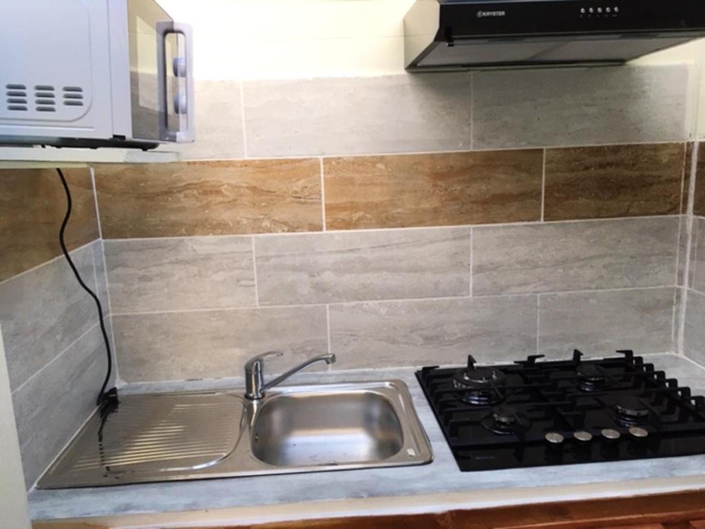 a kitchen counter with a sink and a stove at Charmant bungalow à Hell-Bourg avec vue sur montagnes et jardin in Hell-Bourg
