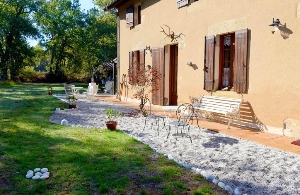 a house with a bench and chairs in the yard at Maison de 4 chambres avec piscine privee jacuzzi et jardin clos a Callen in Callen