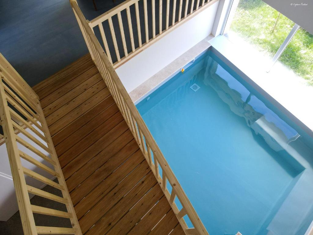 una vista aérea de una piscina con una terraza de madera y una escalera en Villa de 5 chambres avec piscine interieure jardin clos et wifi a Panissieres en Panissières