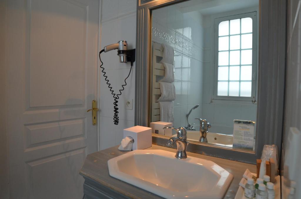 a bathroom with a sink and a mirror at Villa Augeval Hôtel de charme & Spa in Deauville
