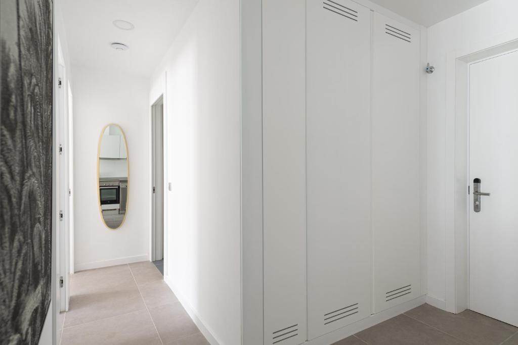 a hallway with white walls and a mirror at Royal Flats in Las Palmas de Gran Canaria
