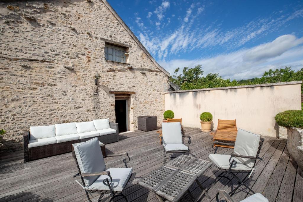 a patio with chairs and a couch and a brick building at La "Petite" Maison in Saint-Romain