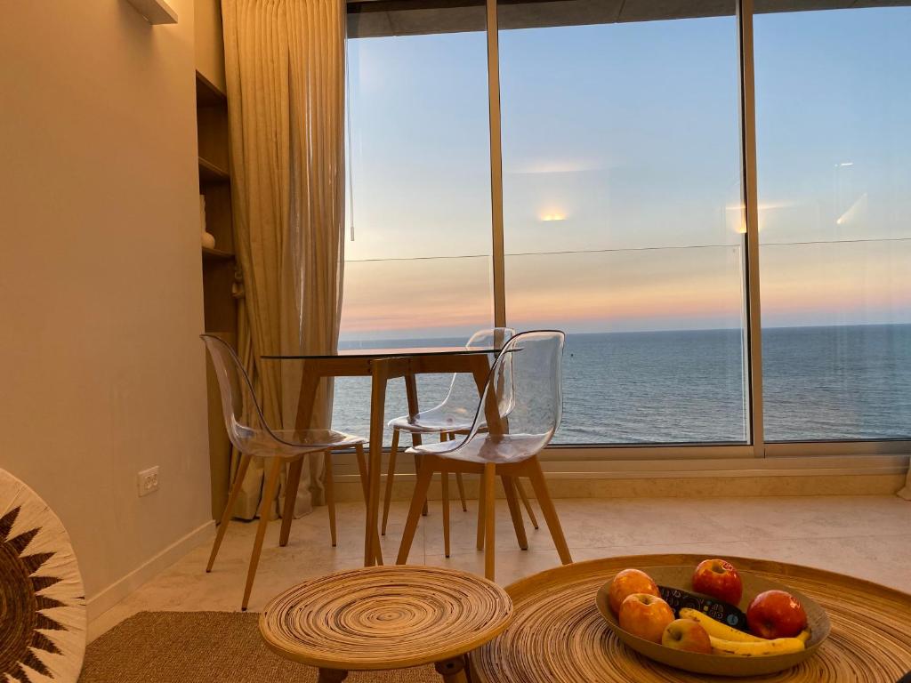 een woonkamer met een tafel en uitzicht op de oceaan bij daniel hotel beach view boutique apt in Herzelia 