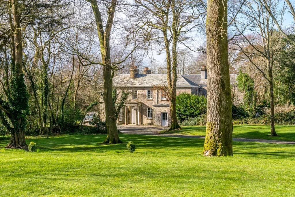 a house in the middle of a field with trees at Secluded Manor House with pool and tennis court in Bodmin