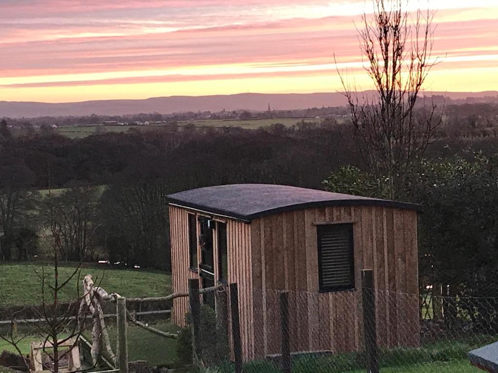 a small wooden building in a field with a fence at Stunning Shepherds Hut rural bliss Dumfries in Dumfries