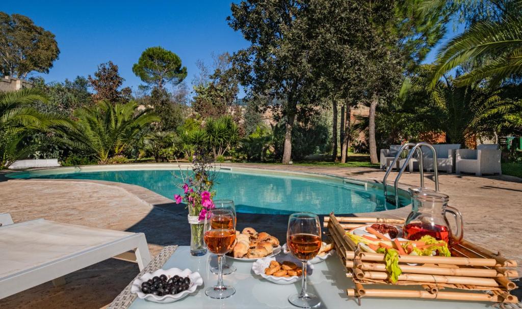 een tafel met wijnglazen en eten naast een zwembad bij Villa Flem Luxury by HDSalento in Montesano Salentino