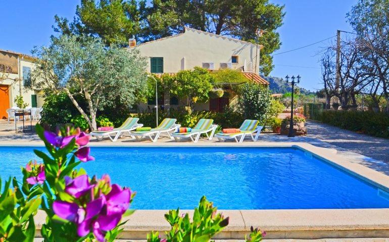 een zwembad met stoelen en een huis bij Casa de Campo con Encanto in Pollença