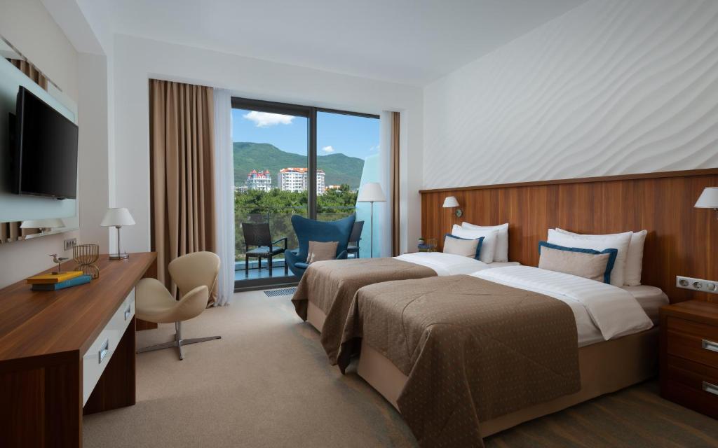 um quarto de hotel com duas camas e uma varanda em Primorie Grand Resort Hotel 5* em Gelendzhik