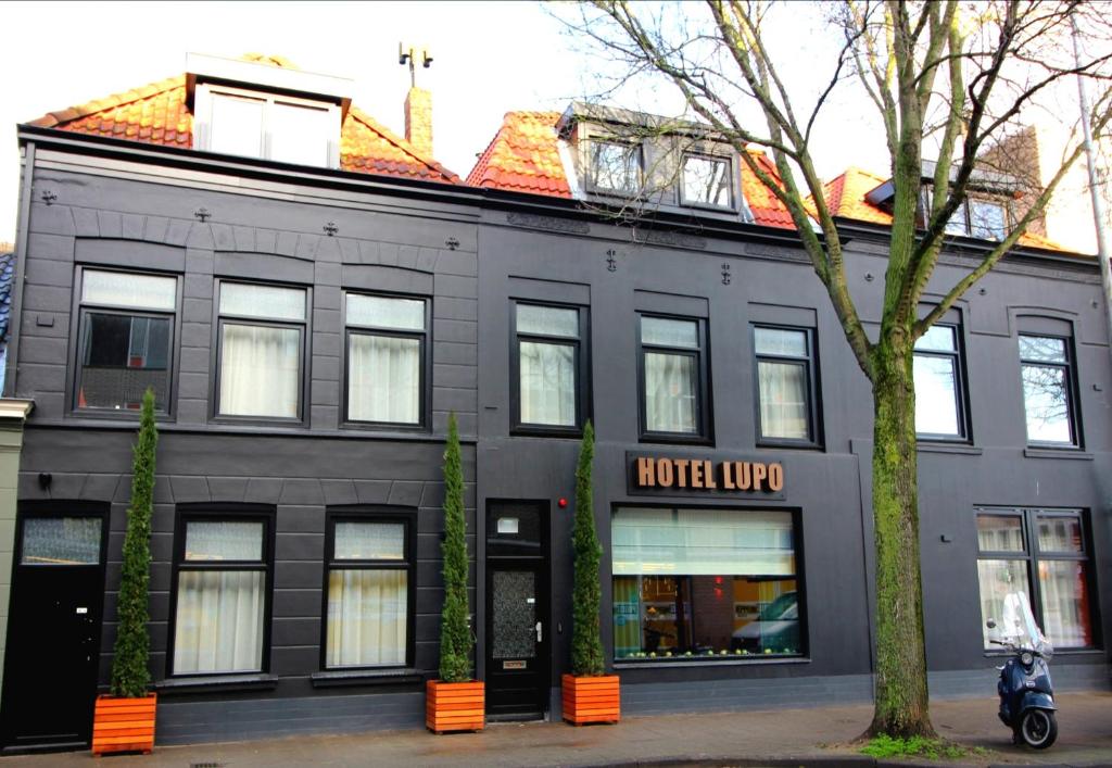 een zwart gebouw met een motorfiets ervoor geparkeerd bij Boutique Hotel Lupo in Vlissingen