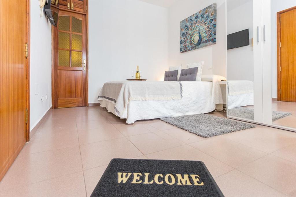 a bedroom with a bed with a welcome mat on the floor at Studio near the Sea and City in Las Palmas de Gran Canaria