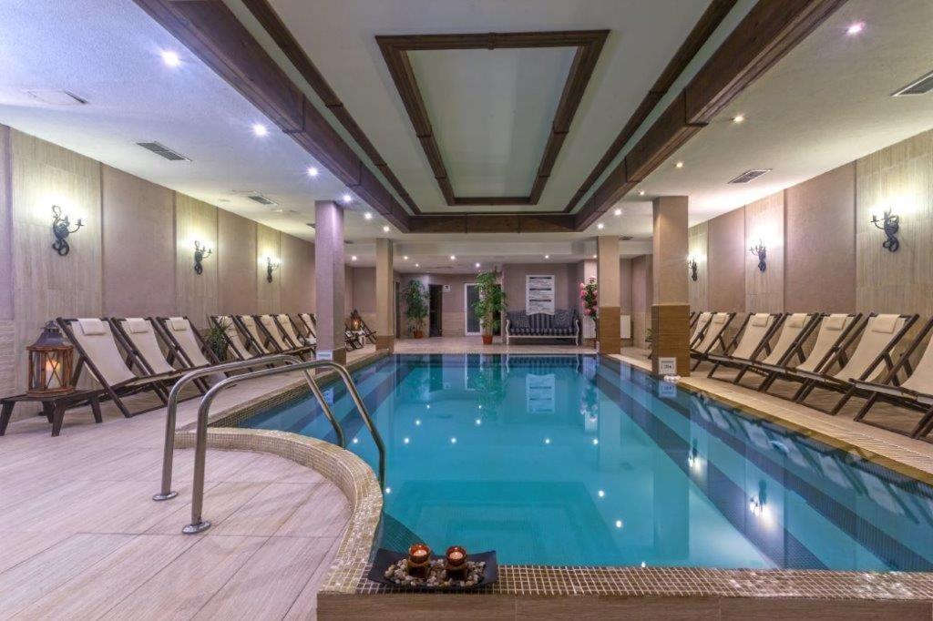 a pool in a hotel with chairs around it at Maria-Antoaneta Residence in Bansko