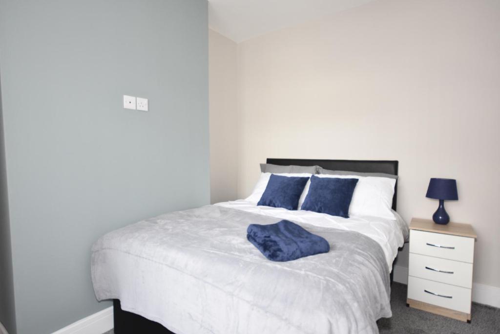 a bedroom with a white bed with blue pillows at Townhouse @ Penkhull New Road Stoke in Stoke on Trent