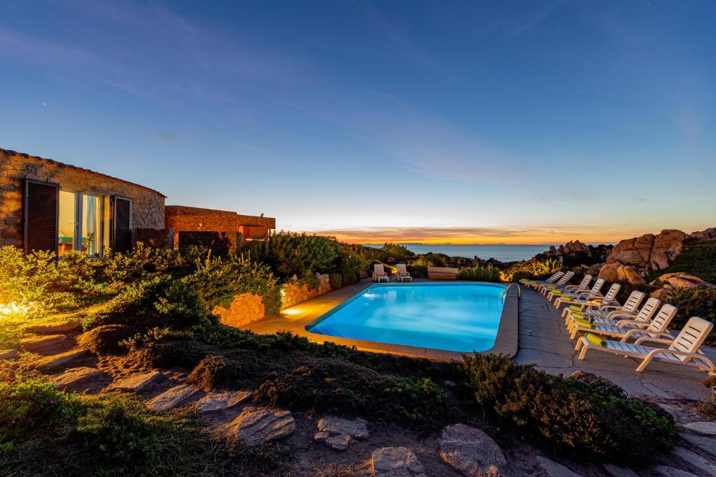 a swimming pool with chairs and a house at Le Sfumature di Melograno in Costa Paradiso