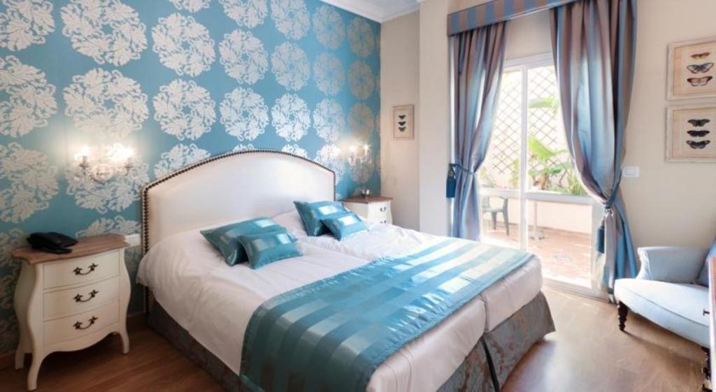 een slaapkamer met een bed met blauwe muren en een raam bij Hotel Central Boutique in Marbella