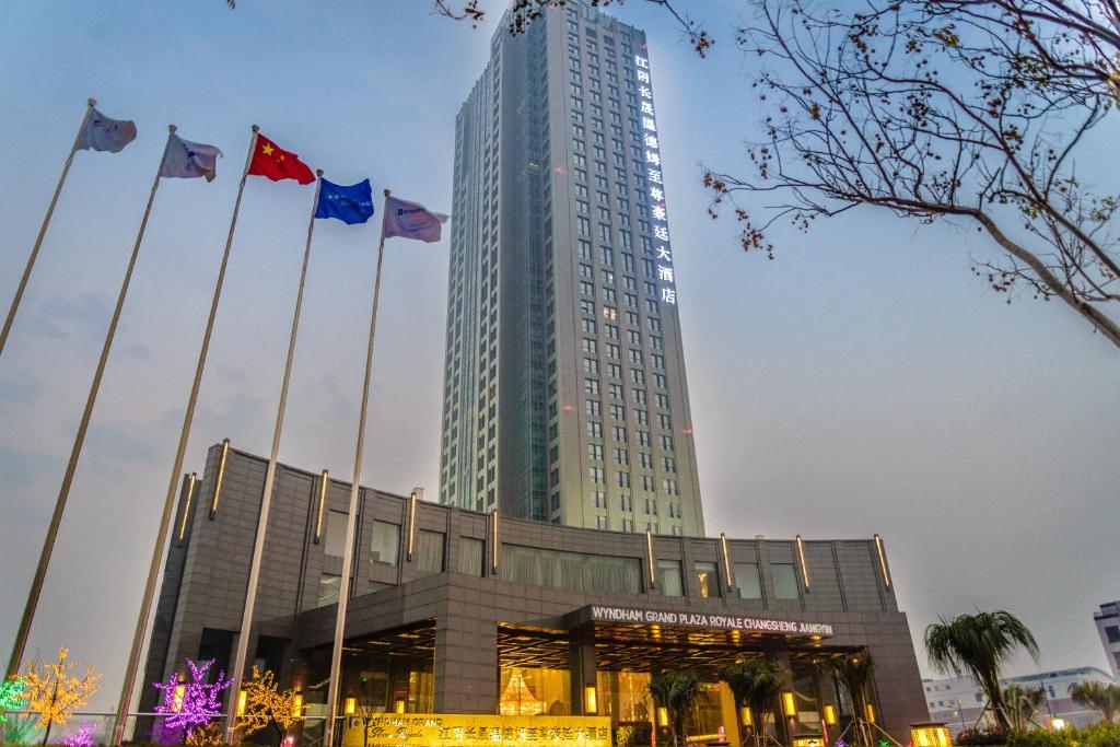 wysoki budynek z flagami przed nim w obiekcie Wyndham Grand Plaza Royale Changsheng Jiangyin w mieście Jiangyin