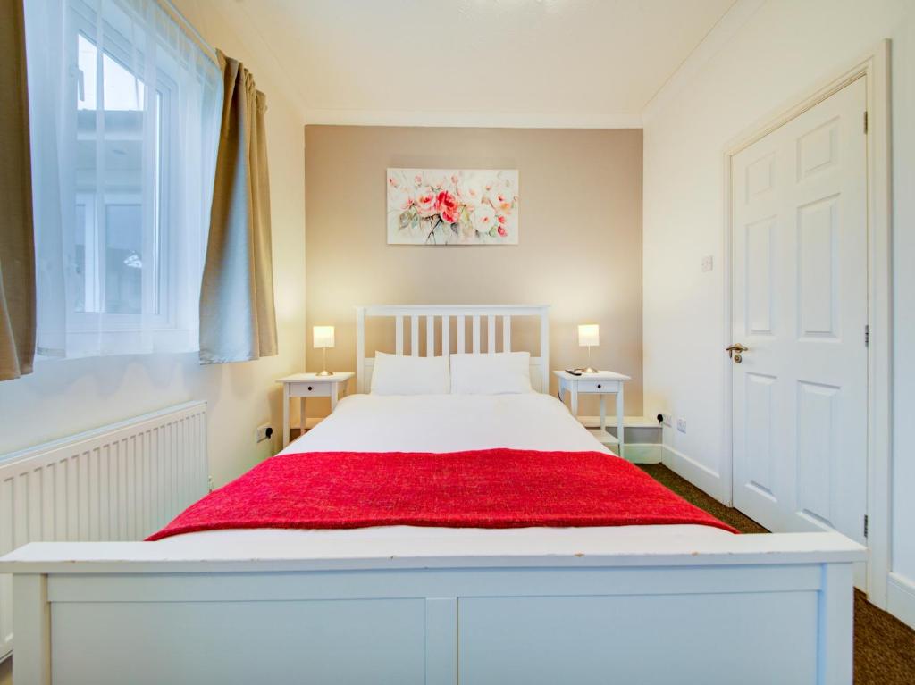 a bedroom with a white bed with a red blanket at The Regent Guest House in Southampton