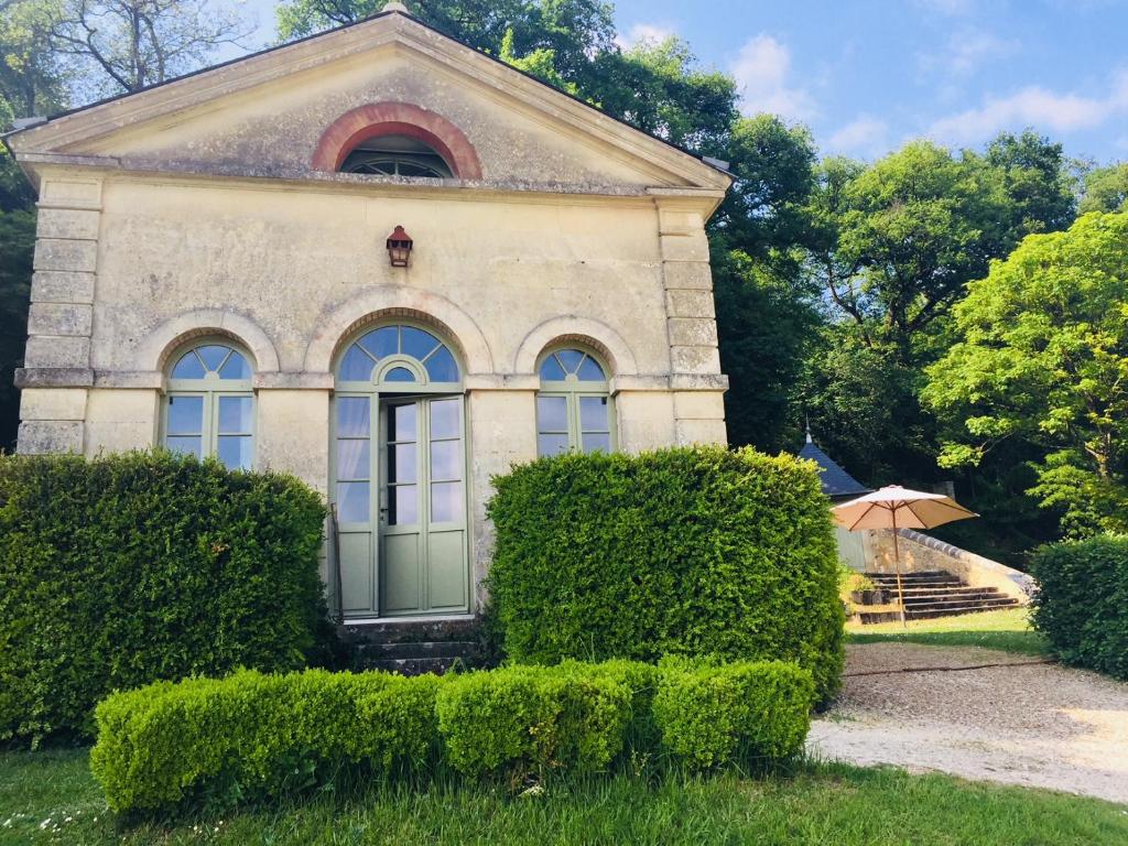 Saint-Paterne-RacanにあるGîte du château d'Hodebertの前に茂みを持つ石造りの家