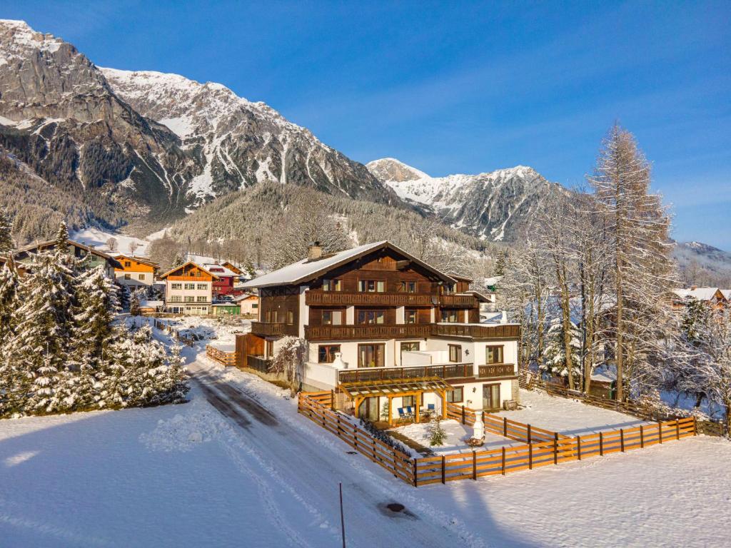 a house in the snow with mountains in the background at Bergidyll Top 1 Gartenwohnung in Ramsau am Dachstein