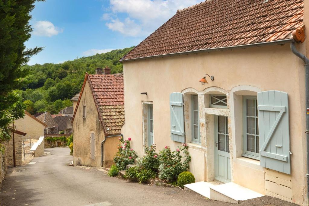 an old house with blue shutters on a street at Les Demeures du Tonnelier, Maison Rue in Saint-Romain