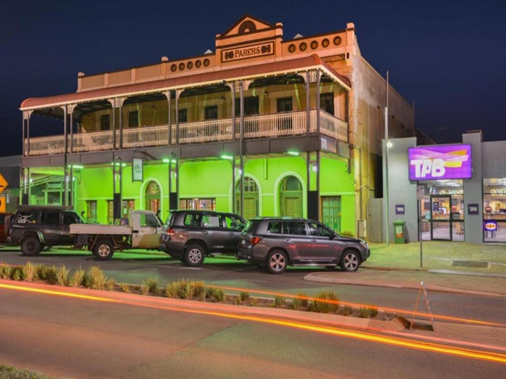 un bâtiment vert avec des voitures garées dans un parking dans l'établissement Albion Hotel, à Kalgoorlie