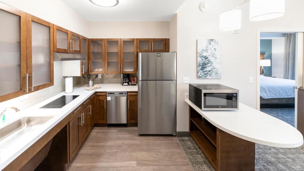 a kitchen with wooden cabinets and a stainless steel refrigerator at Staybridge Suites - Naples - Marco Island by IHG in Naples