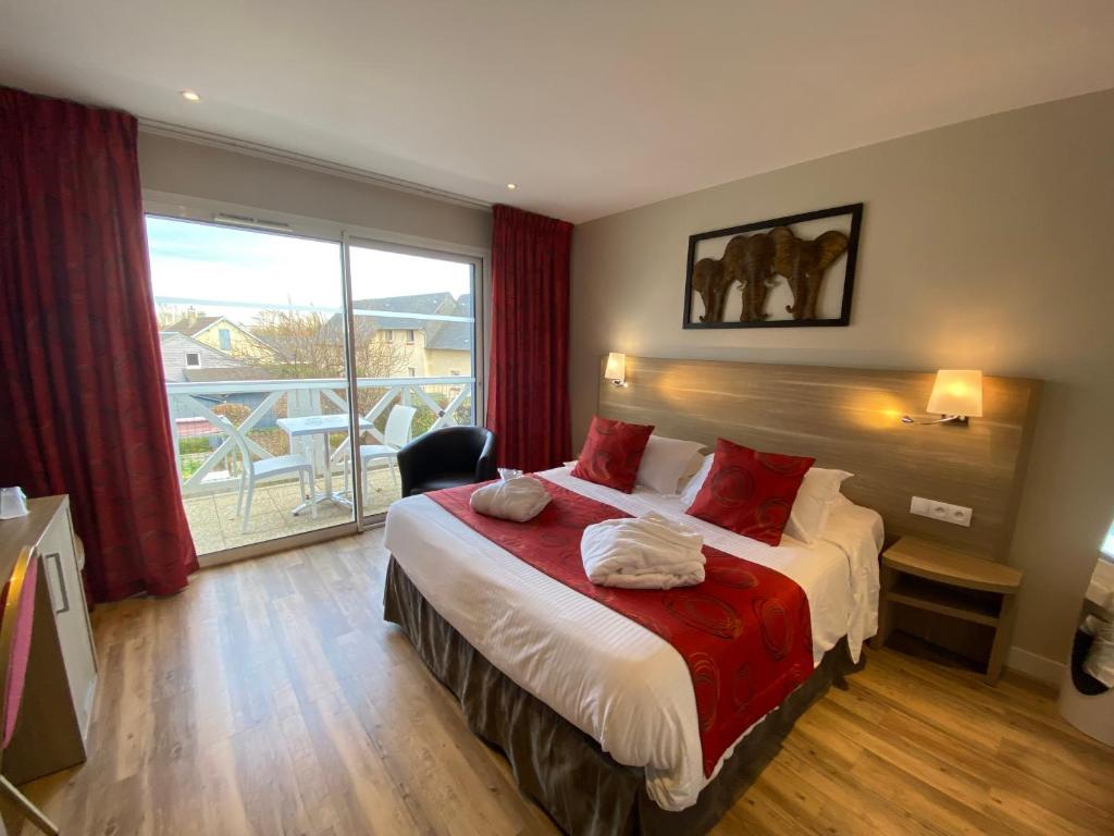 a bedroom with a bed and a large window at Contact hôtel - Hôtel Les Bleuets & SPA in Honfleur