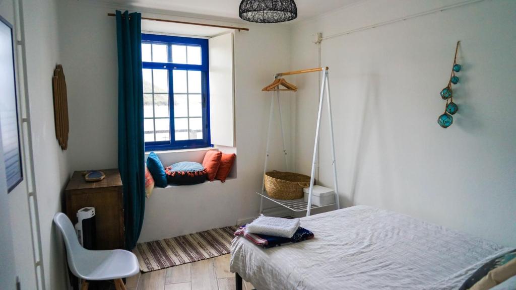 een slaapkamer met een bed, een raam en een schommel bij Casa Três Picos in Horta