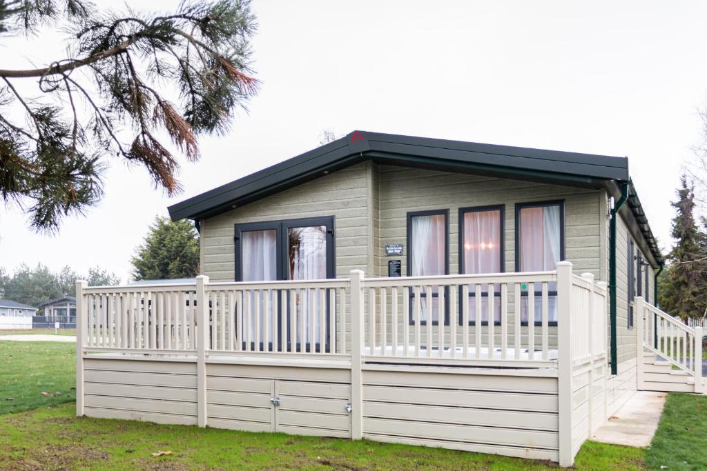 a small house with a white fence at The White Rose Lodge with Hot Tub in York