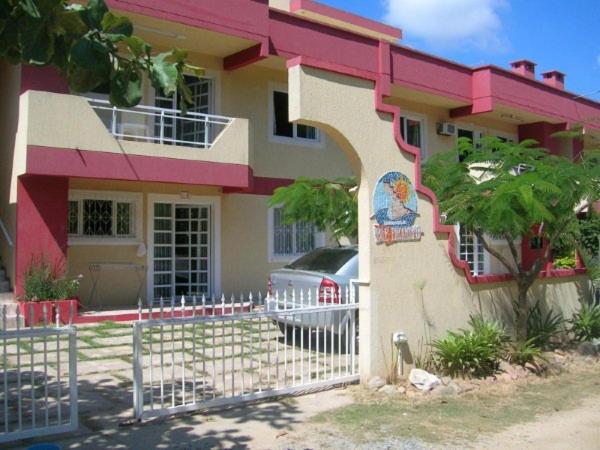 a pink and white house with a white fence at Departamentos Vale Encantado in Bombinhas