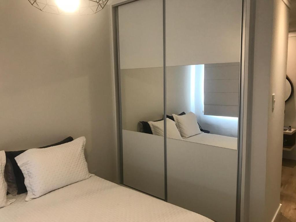 a bedroom with a mirror and a bed with white pillows at Apartamento Frente ao Mar Santos in Santos
