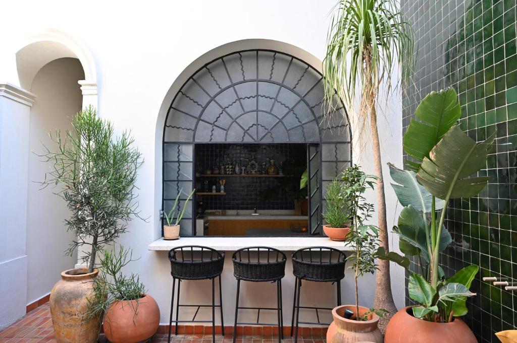 a room with a fireplace with four chairs and plants at Casa Kali by Barrio México in Guadalajara