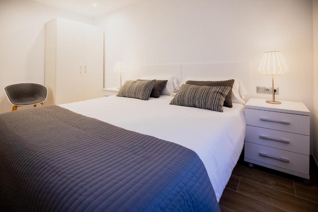 um quarto com uma grande cama branca e uma cadeira em El Niu de Escaldes em Escaldes-Engordany